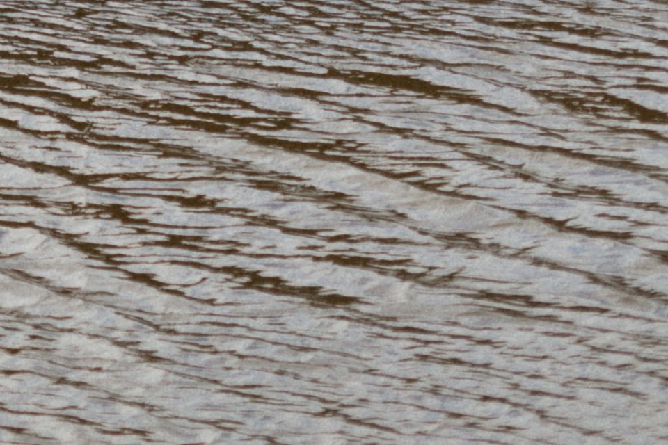 Close-up texture of rippling water surface with diagonal wave patterns.
