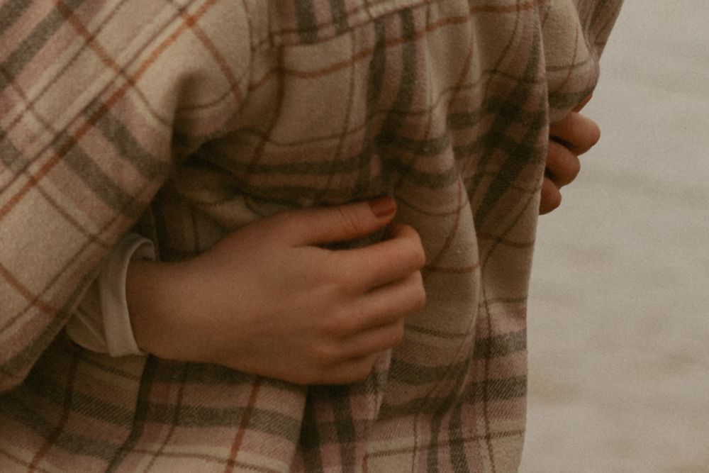 Close-up of hands holding plaid fabric in warm lighting.