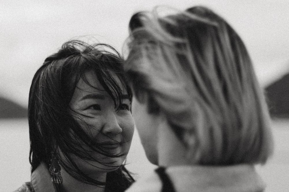 Two people share an intimate black and white moment outdoors.