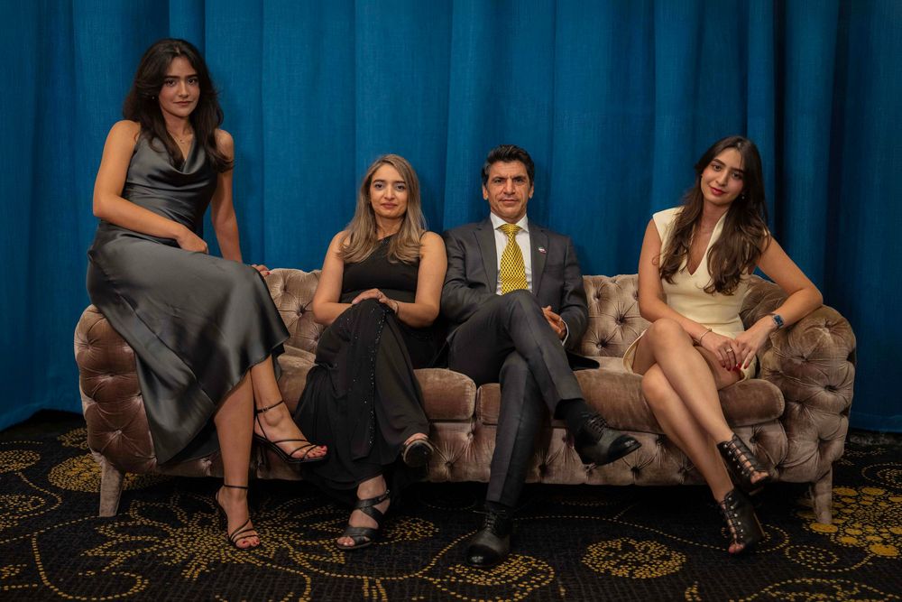 Group lounging on floor against blue curtain backdrop in casual setting.