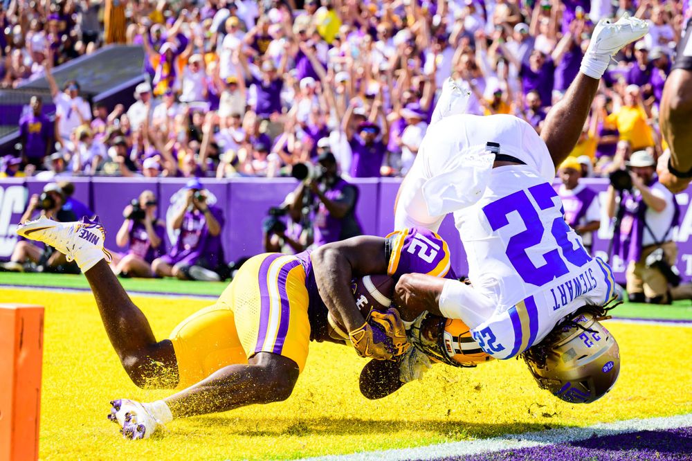 Football players diving and tackling on field during intense game play.