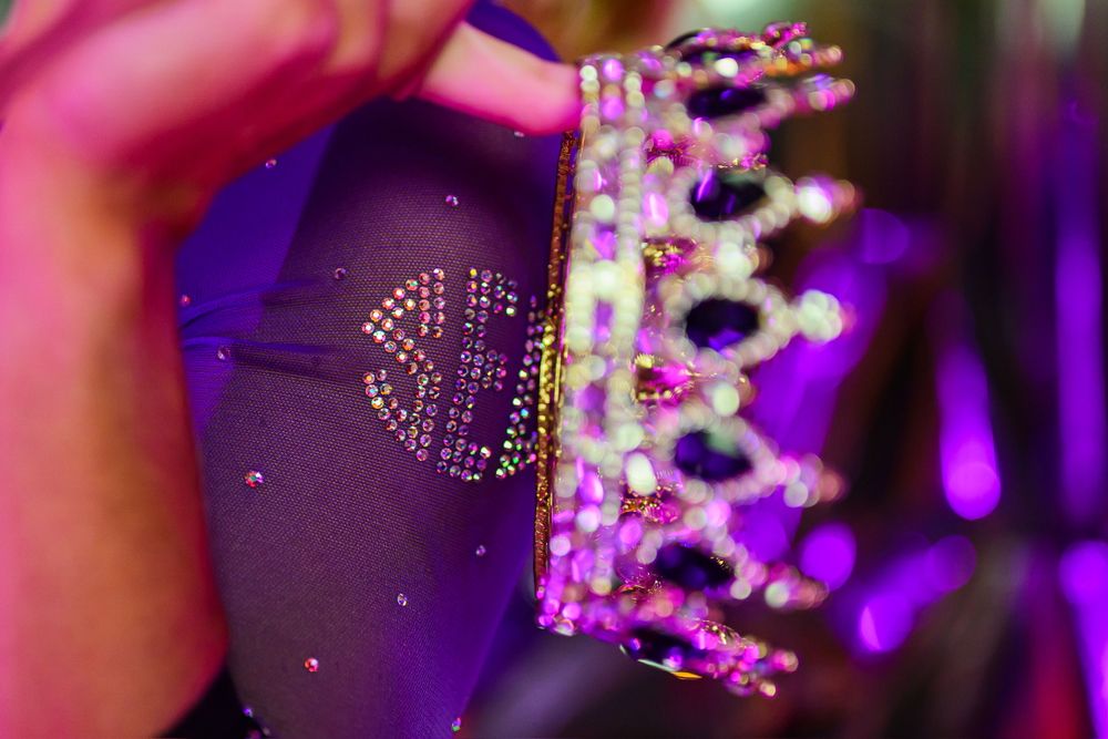 Close-up of sparkly purple crown with jewels in dramatic lighting.