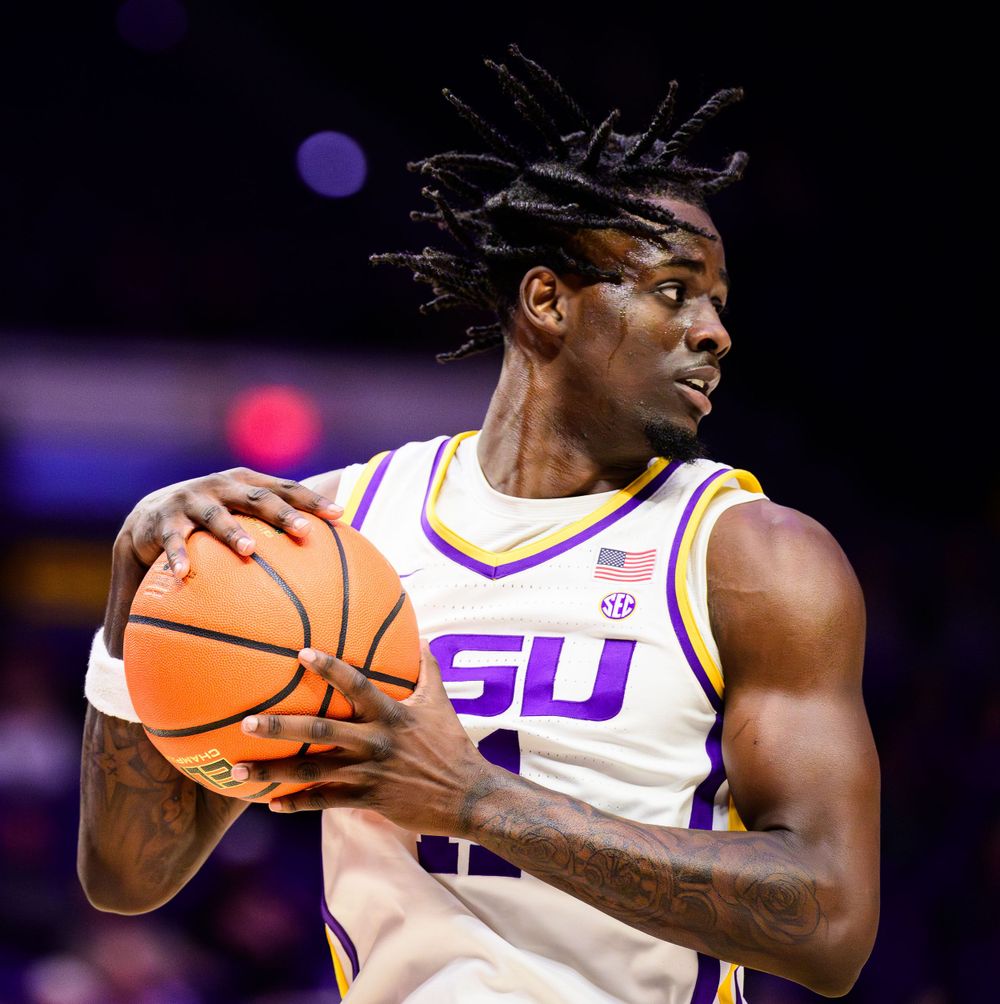 Basketball player in white LSU uniform holding ball during game.