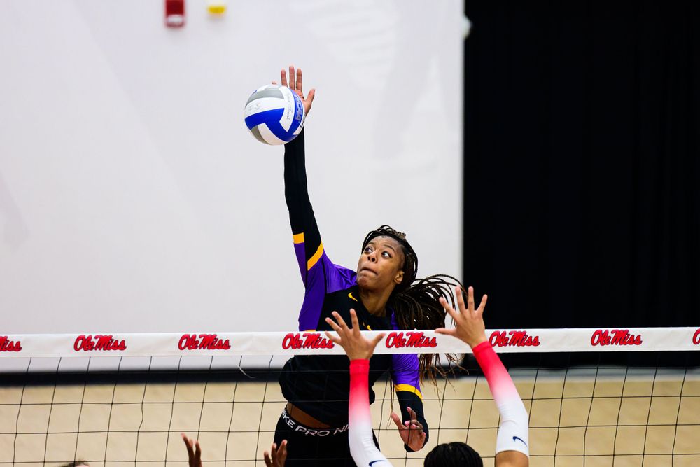 Volleyball player leaps high to spike ball during intense match play.
