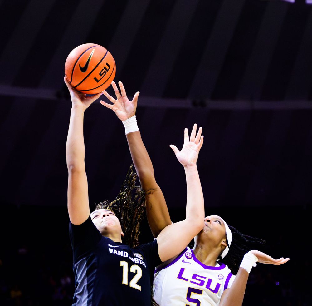 Players battle for rebound under basketball hoop during intense game action.