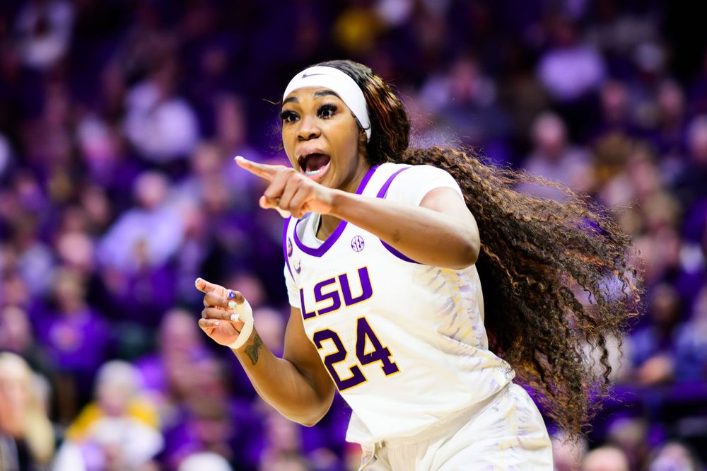Athletes celebrate during basketball game in purple and white uniforms.