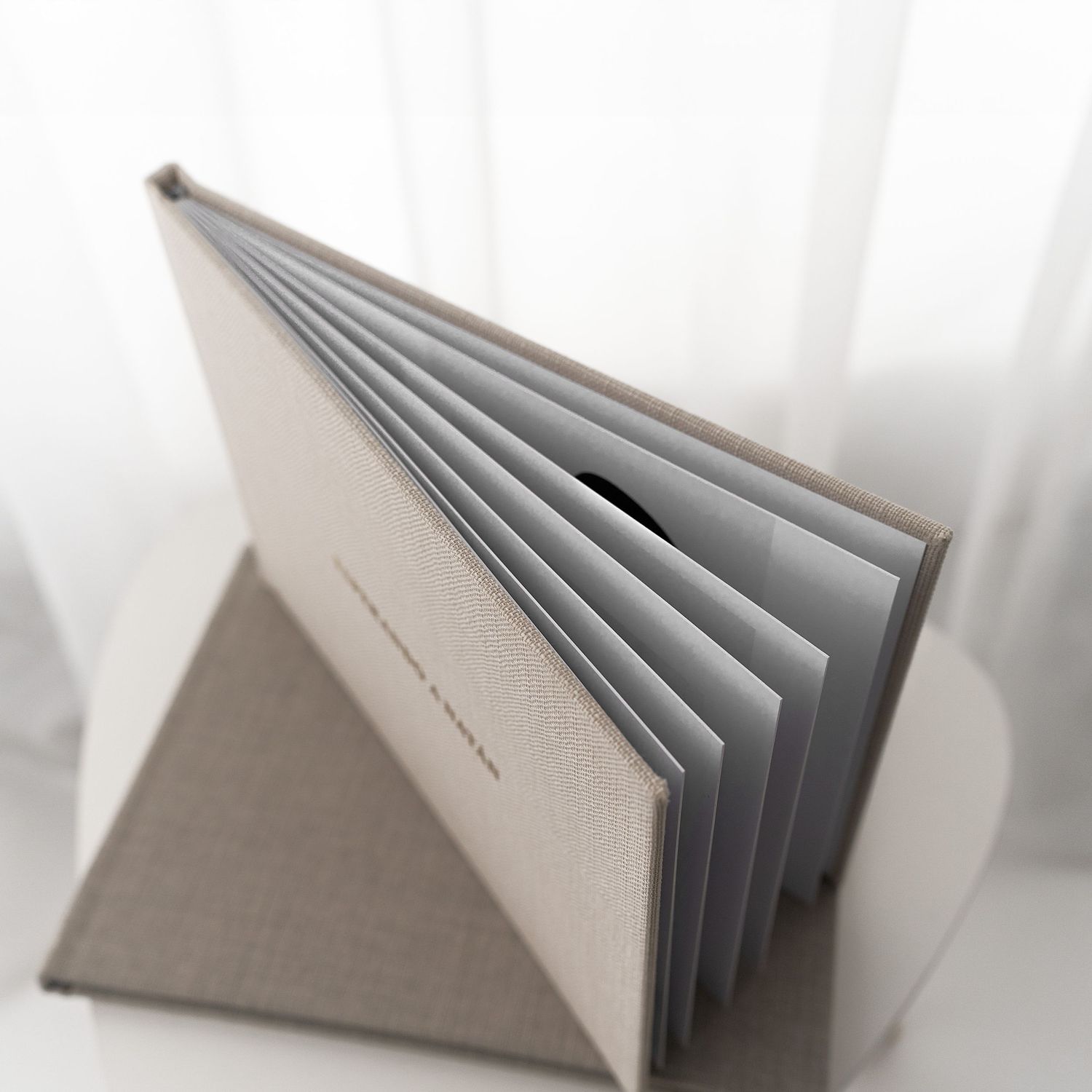 Minimalist photo album with gray pages fanned open against white background.