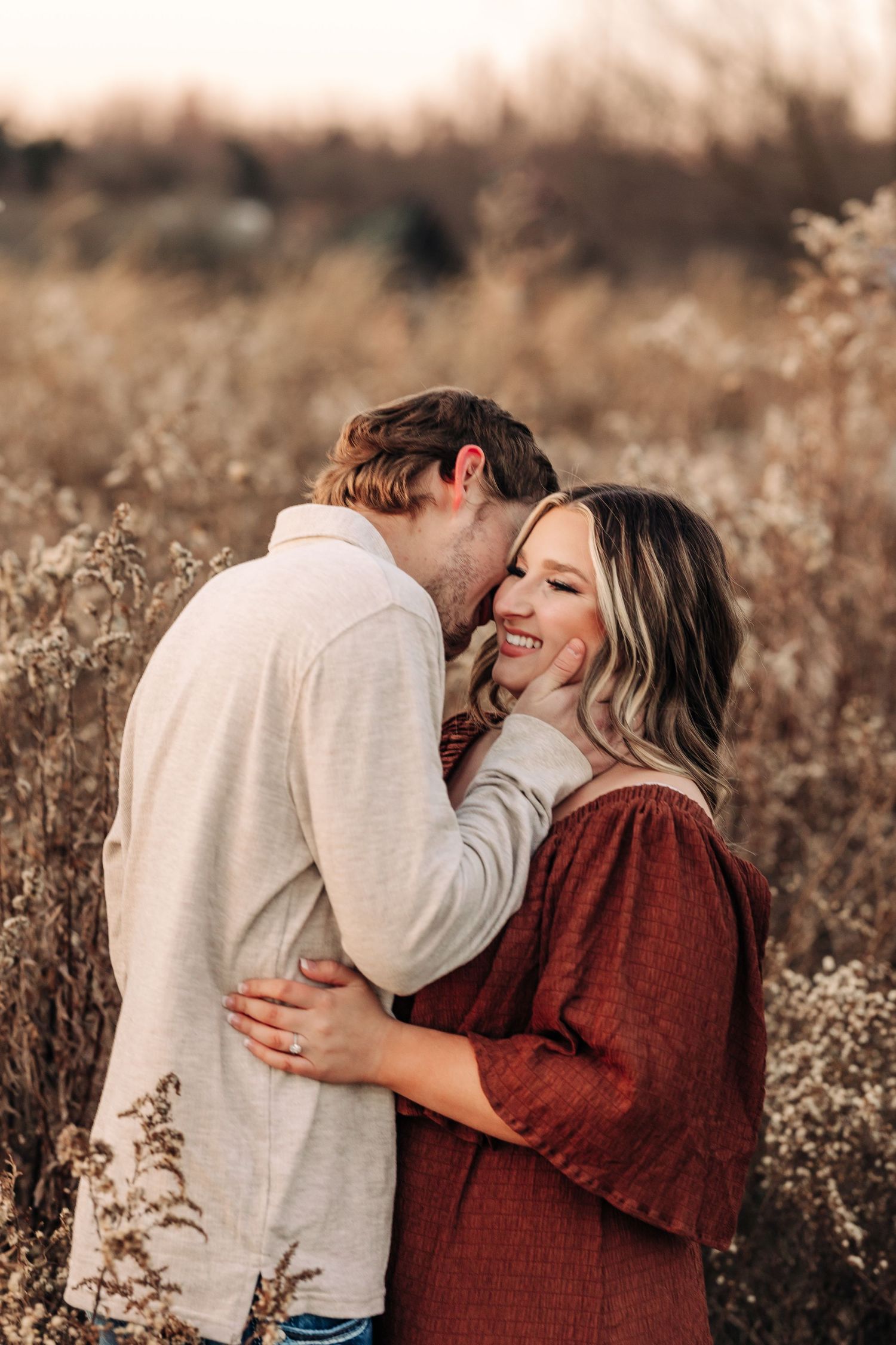Couple shares intimate moment in autumn field during golden hour.