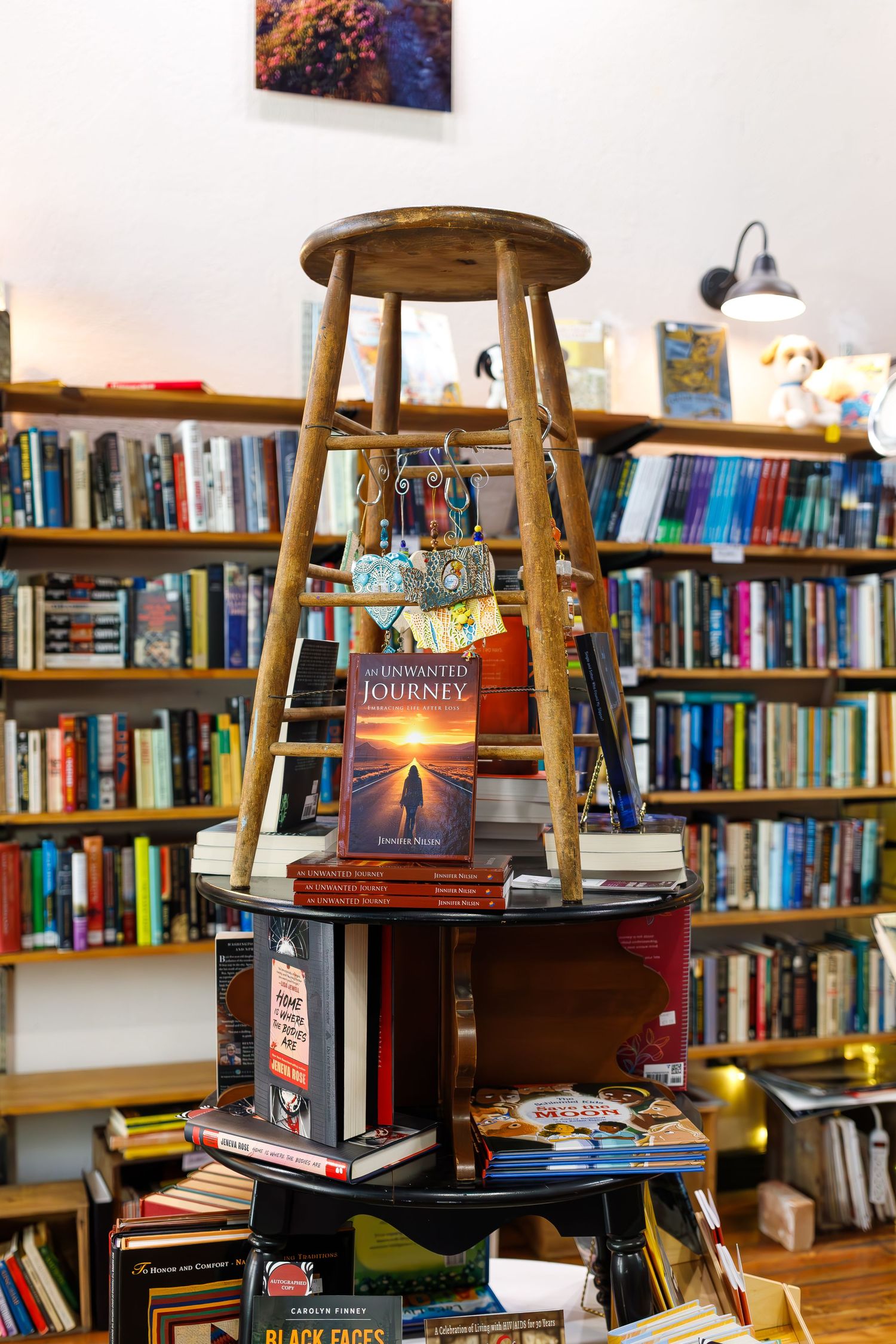 Wooden stool used as creative book display stand against wall of bookshelves.