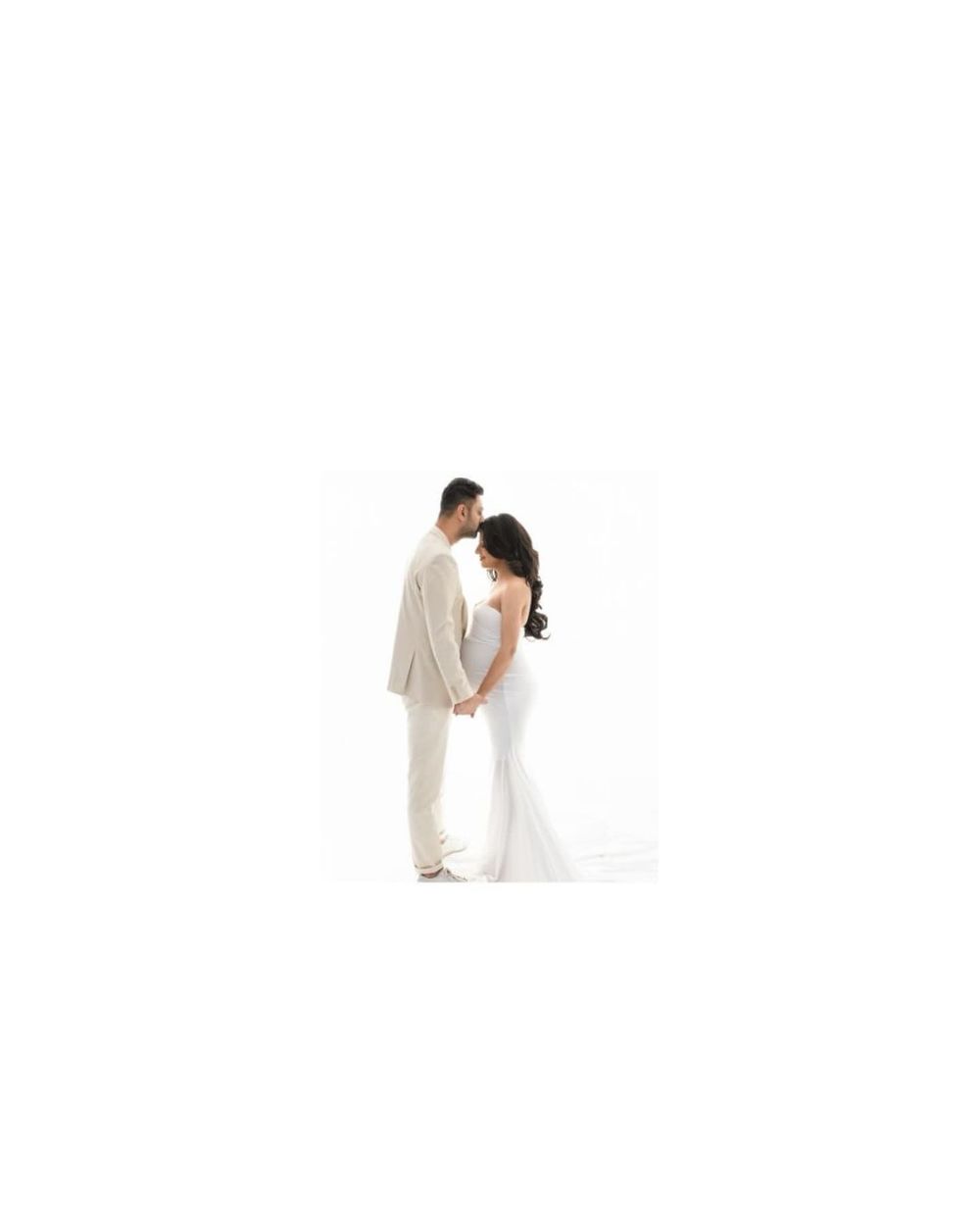 Intimate maternity portrait in white attire against clean backdrop.