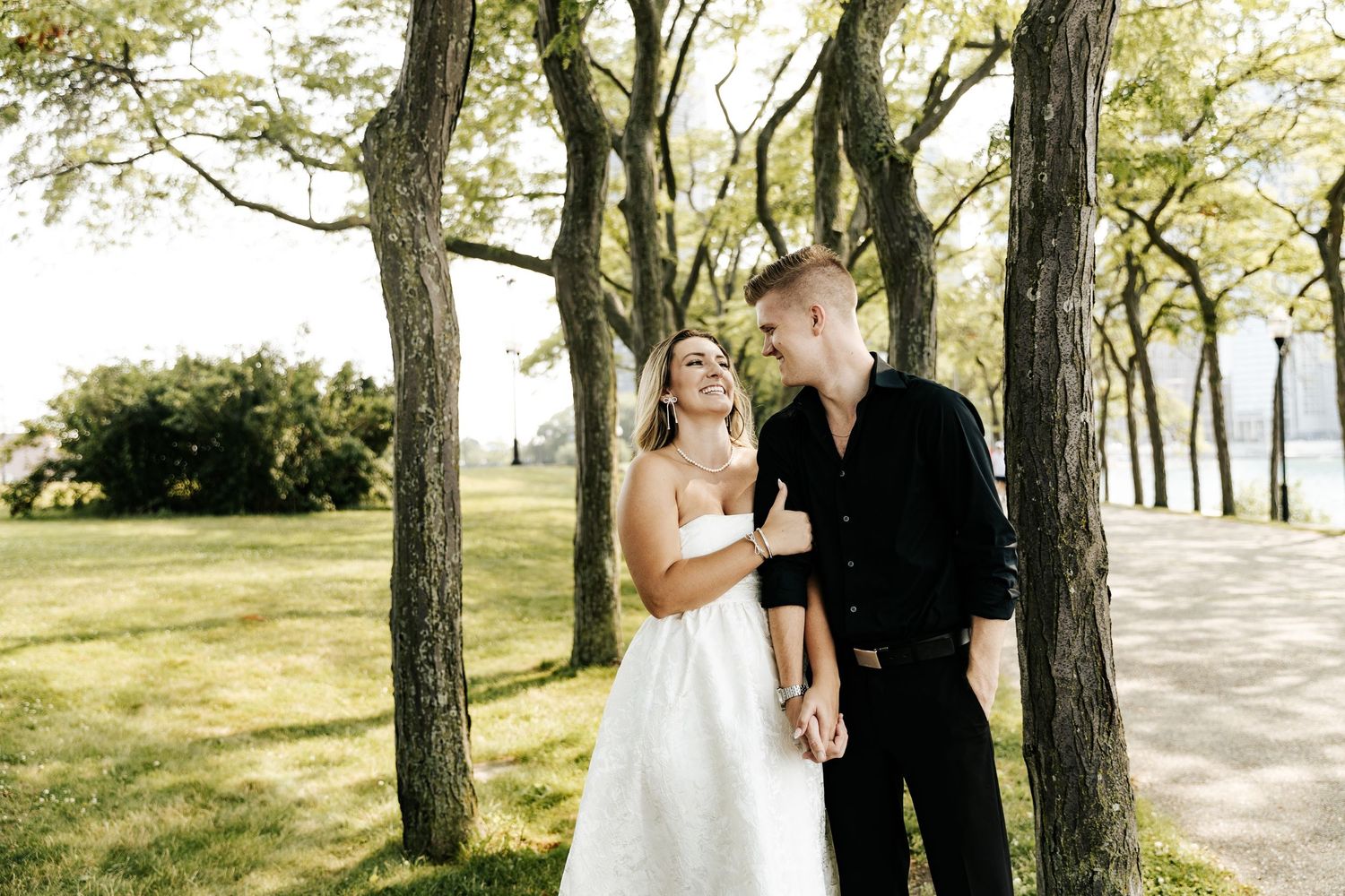 Candid romantic moment between couple embracing outdoors near trees.