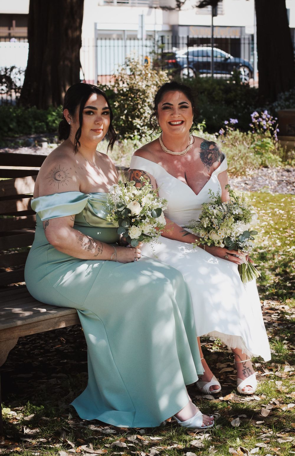 Bride and daughter sitting on a bench smiling at the camera at Portsmouth wedding captured by Shayla Bloom photography