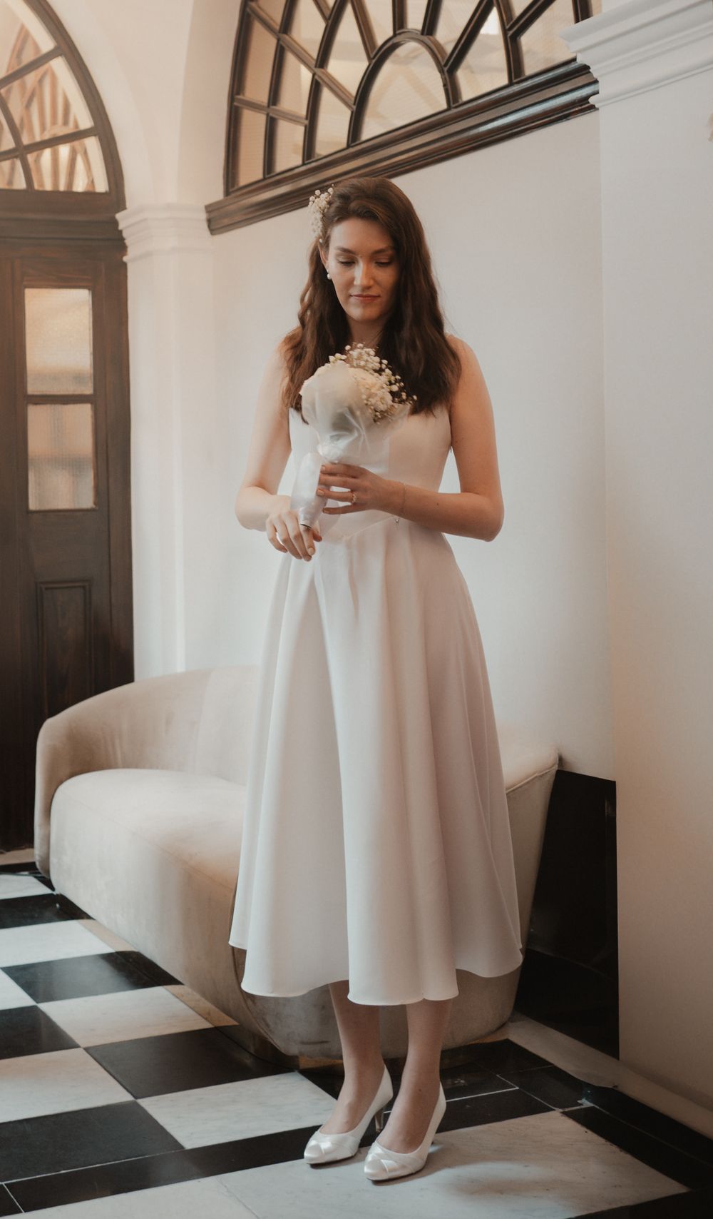 Bride at an intimate Chelsea wedding standing and looking at her bouquet captured by Shayla Bloom Photography