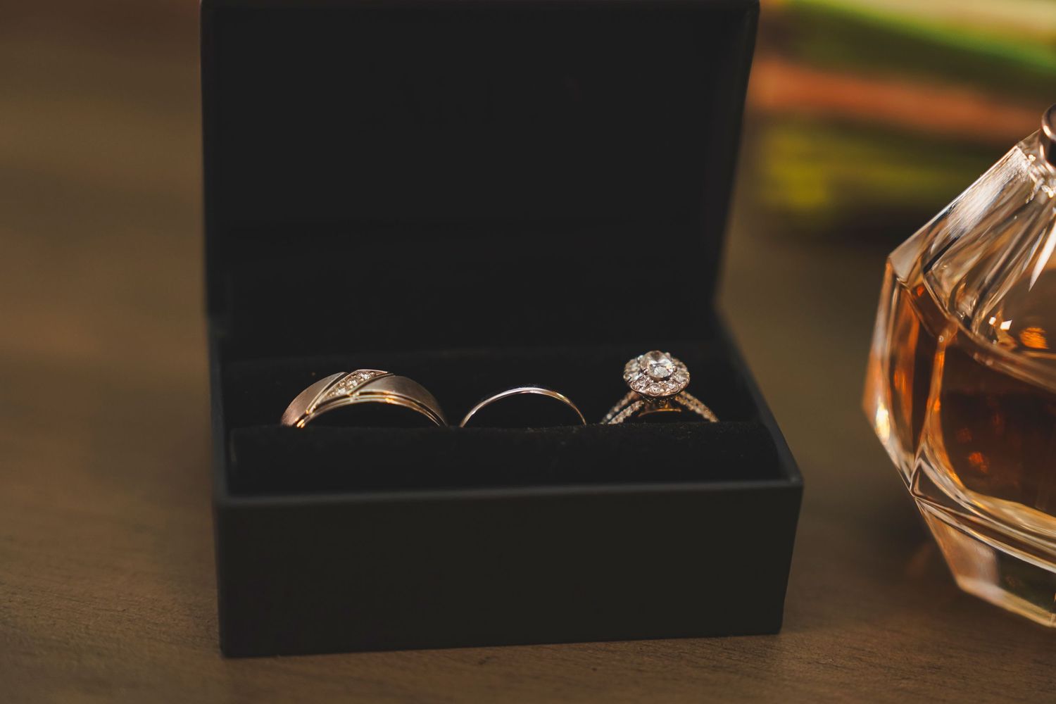 Wedding rings and jewelry arranged on dark surface with elegant lighting.