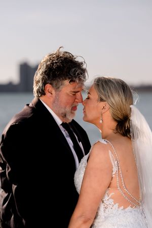 Intimate moment between newlyweds with waterfront skyline in the background.