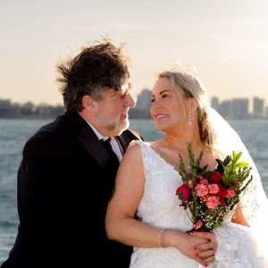 Newlyweds share a tender moment by the water during golden hour.