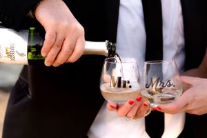 Champagne being poured into Mr. and Mrs. wedding glasses with red nail polish detail.