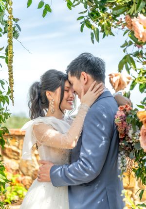 Intimate wedding moment captured under garden arch with soft natural lighting.