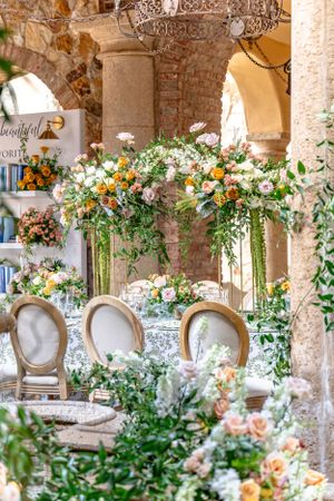 Elegant outdoor wedding reception with lush floral arrangements and French country chairs.
