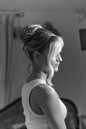 A side profile portrait in black and white shows a person with hair in a messy updo wearing a sleeveless white top.
