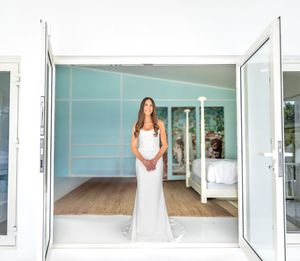 Beautiful wedding dress silhouette standing in a modern room with turquoise walls and French doors.