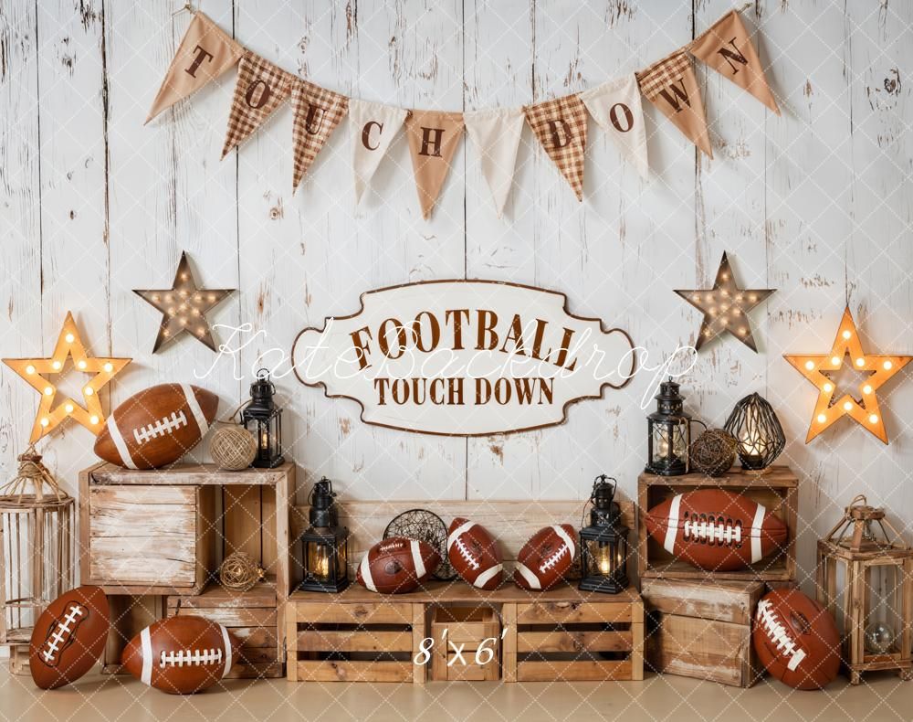 A rustic sport themed party setup with wooden crates, footballs, lanterns, star lights, and burlap touchdown banner decorations.