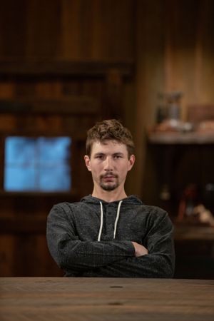 A man in a gray hoodie sits at a wooden table in a warmly lit room with crossed arms.
Commercial Photography
Gold Rush