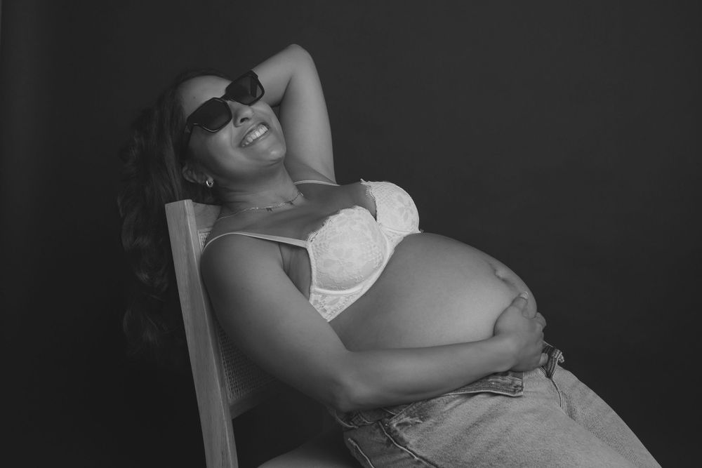 Black and white maternity portrait showing relaxed pose in casual attire.