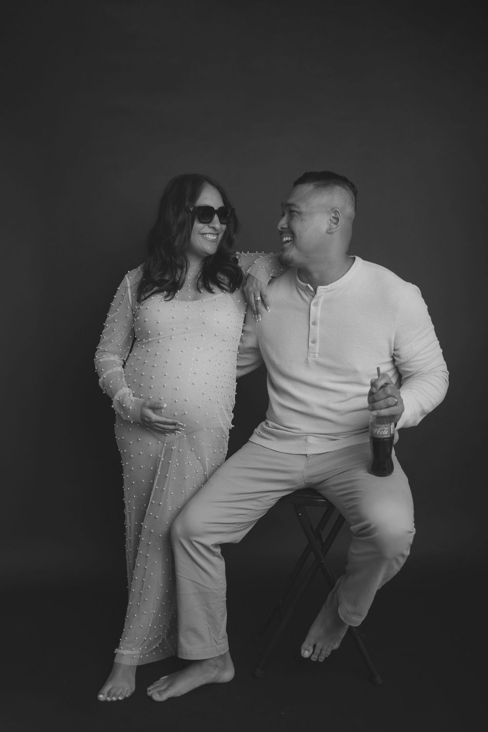 A black and white maternity photo shoot against a dark background.