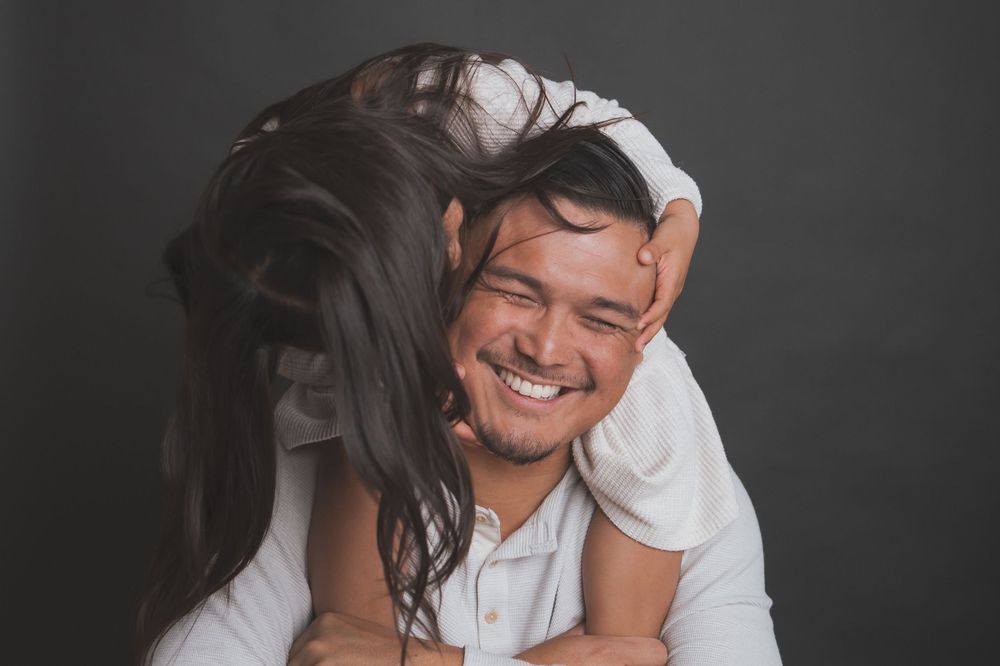 A joyful candid moment captured against a dark backdrop during a maternity photoshoot.