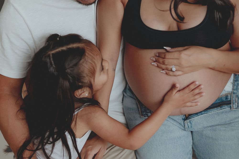 An intimate maternity moment captured with hands lovingly touching a pregnant belly.