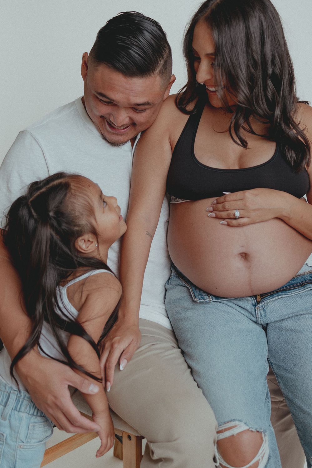 Intimate family portrait capturing a tender moment during pregnancy.