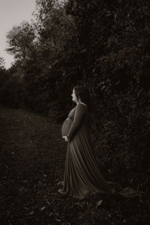 Silhouette of person in flowing dress walking through dark wooded area.