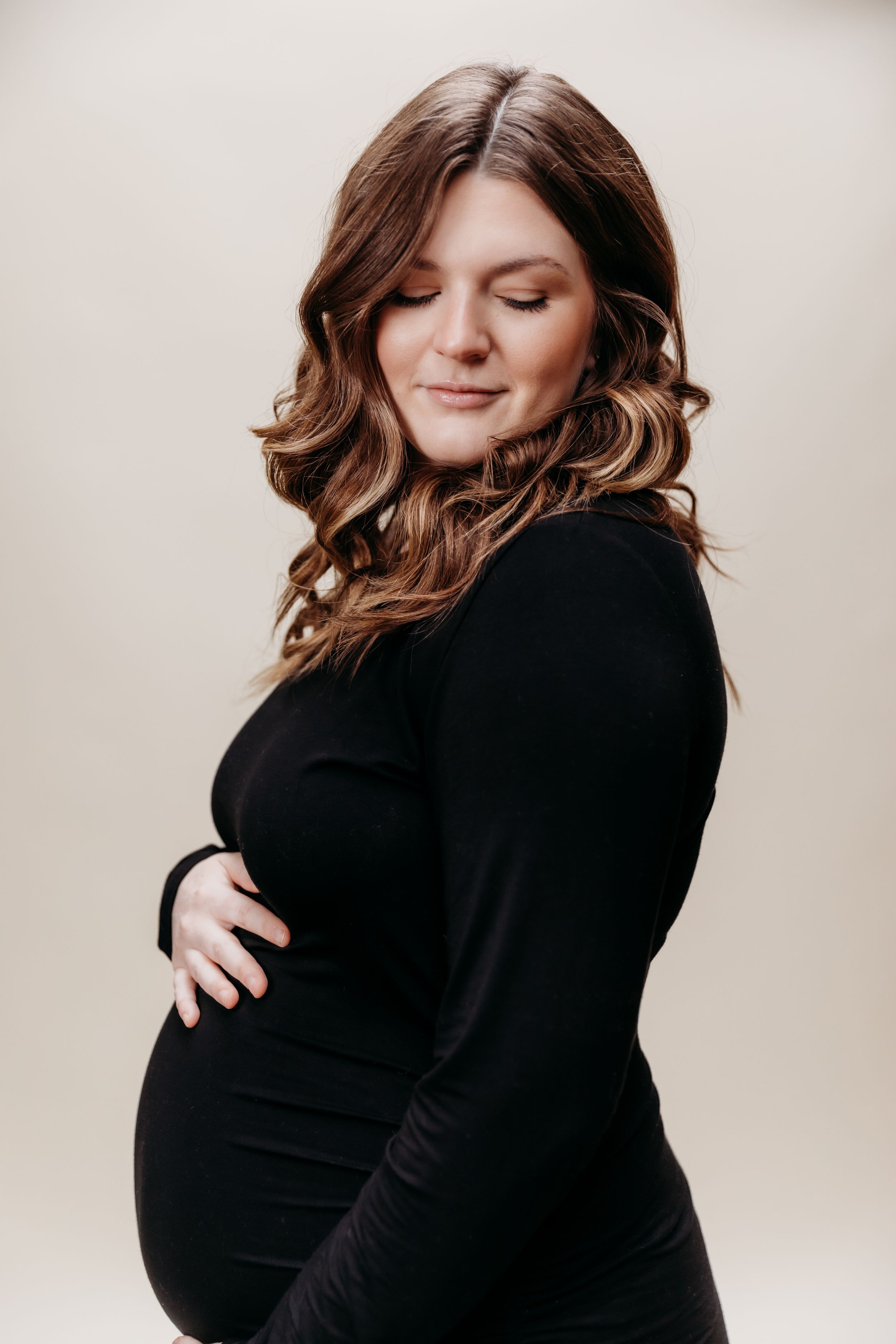 A series of intimate maternity photos showing a woman in a black sweater embracing her baby bump.