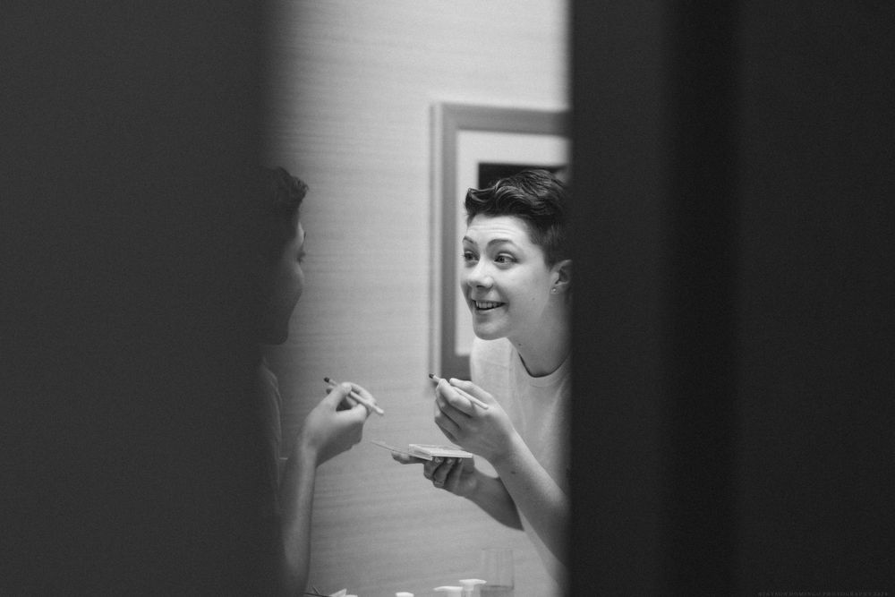 A black and white candid moment capturing preparation with joyful expressions.