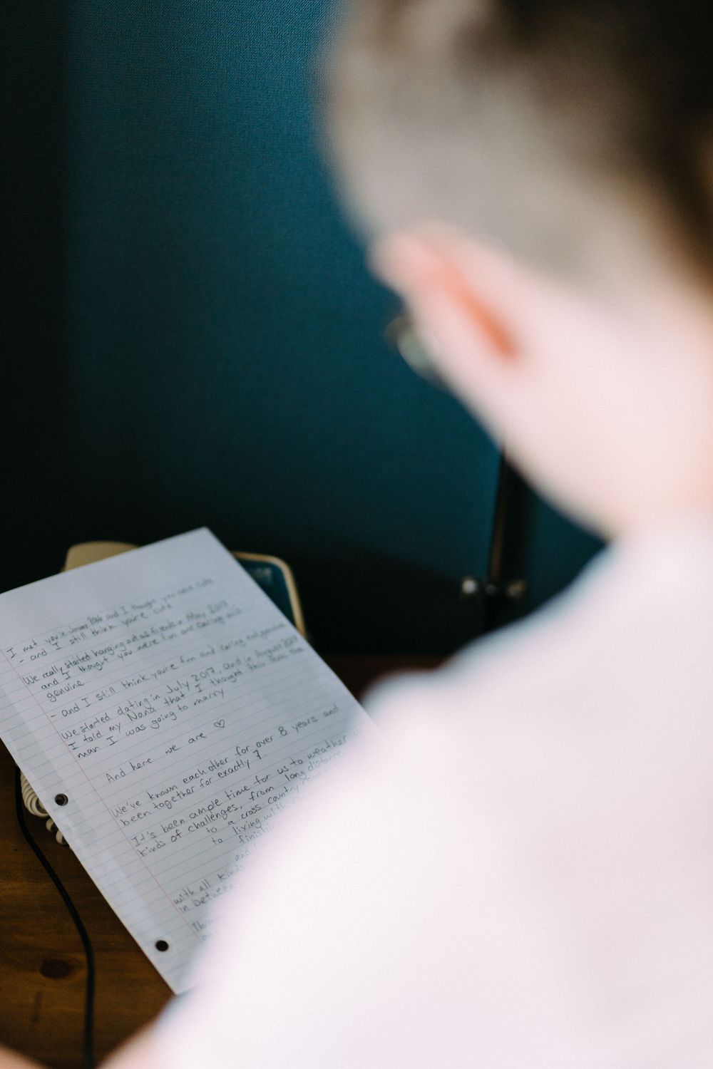 Close-up shot of handwritten notes on lined paper during wedding preparation.