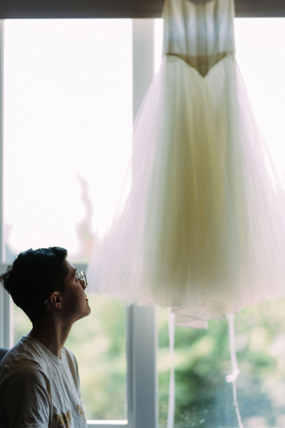 Wedding dress displayed near window with natural light streaming through.