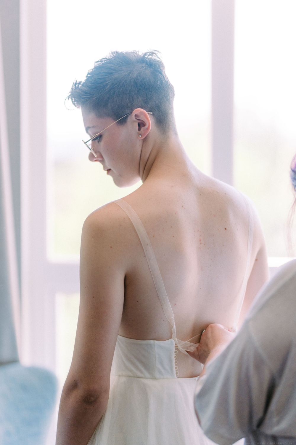 Wedding dress fitting scene with delicate white fabric details.