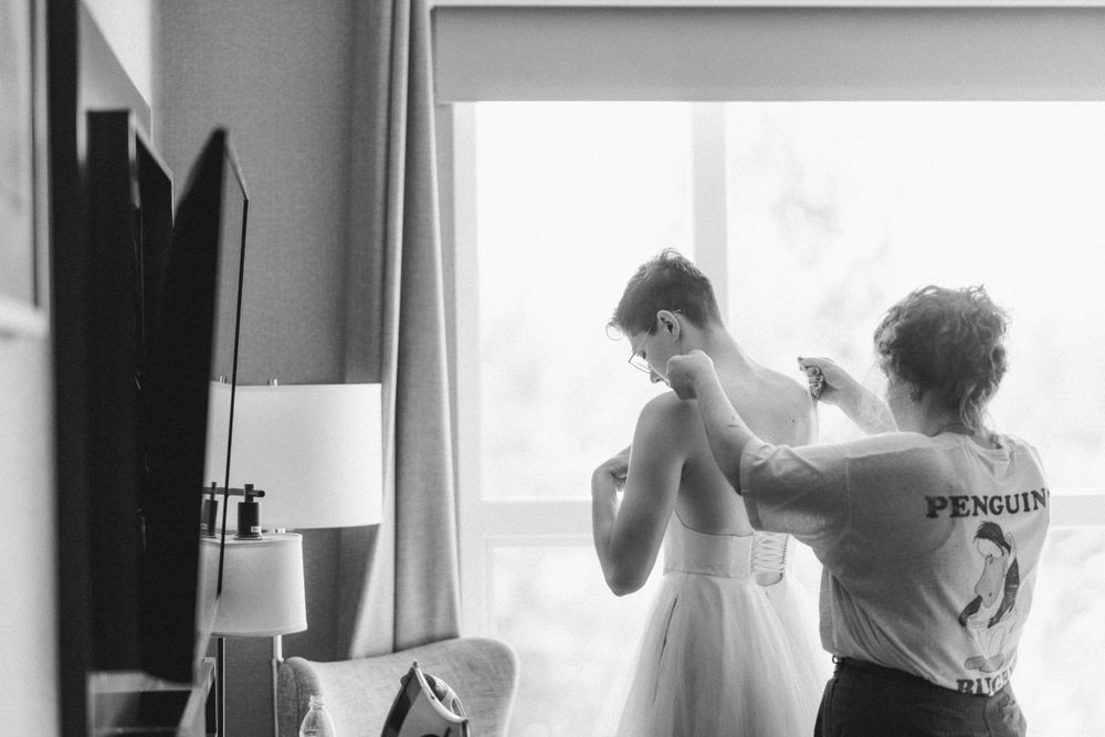 Black and white photo showing wedding dress preparations near a bright window.