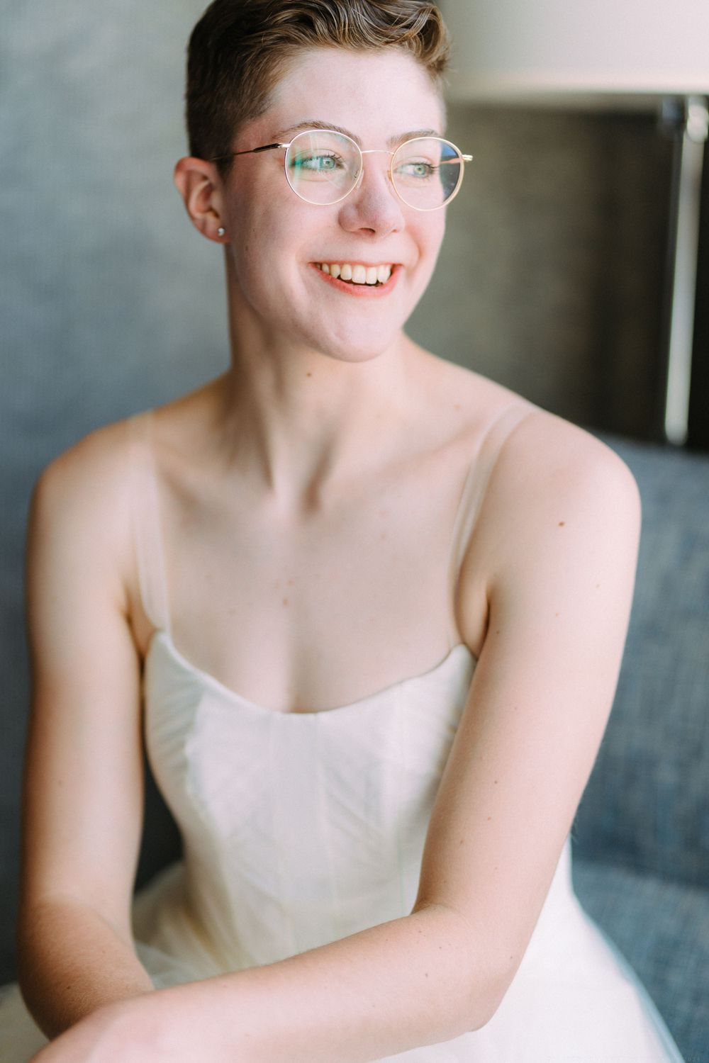 Portrait in natural light showing person wearing glasses and white wedding attire.