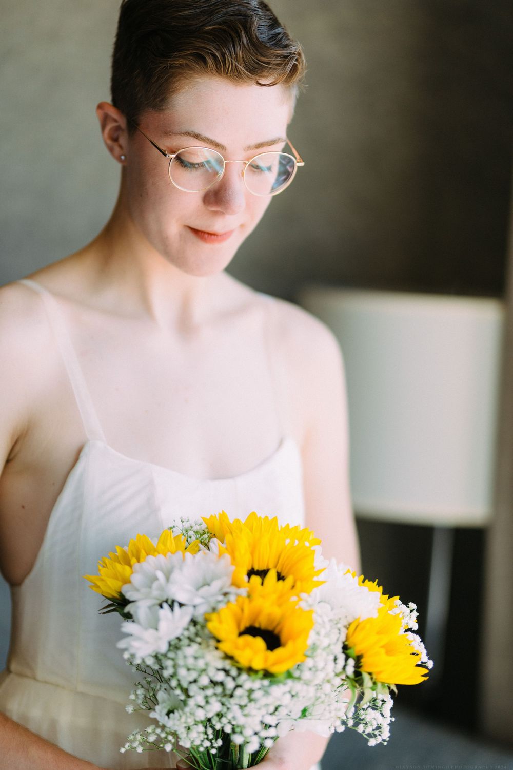 A gentle portrait with sunflowers and baby's breath bouquet against a dark background.
