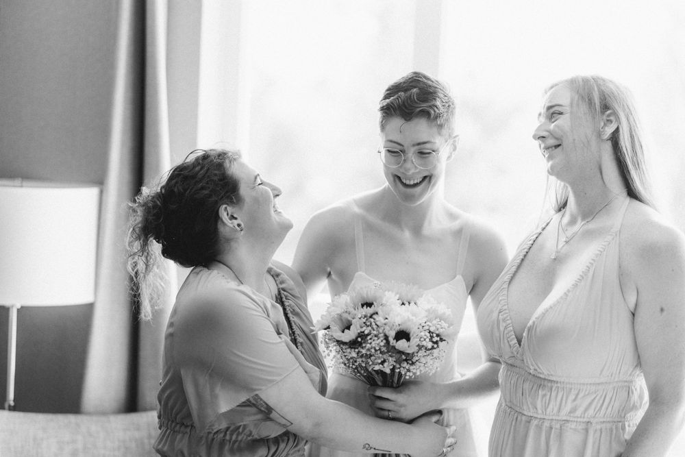 Black and white candid moment showing joyful laughter during wedding preparations.