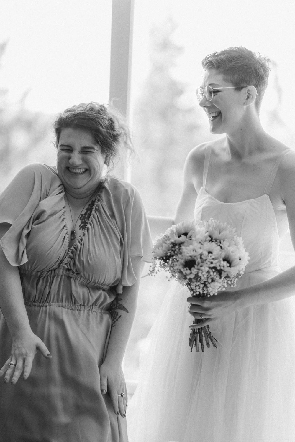 Black and white photo capturing shared laughter during a wedding celebration.