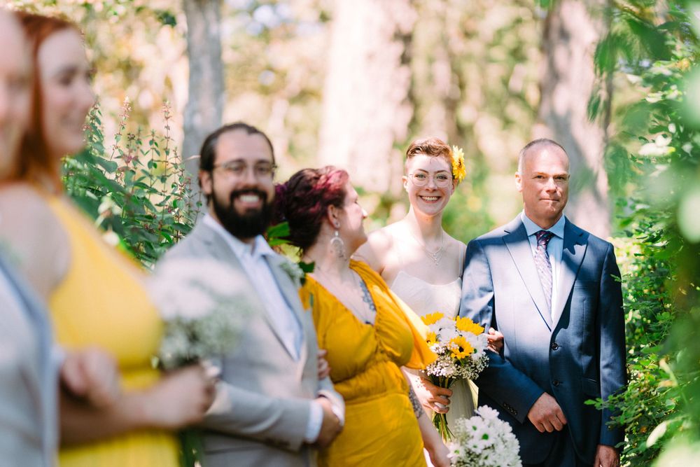 Wedding ceremony in a garden setting with sunlight filtering through trees.