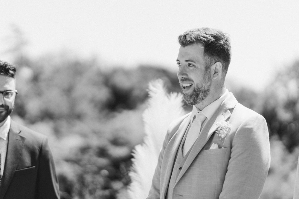 Black and white candid shot showing joyful emotion during outdoor wedding ceremony.