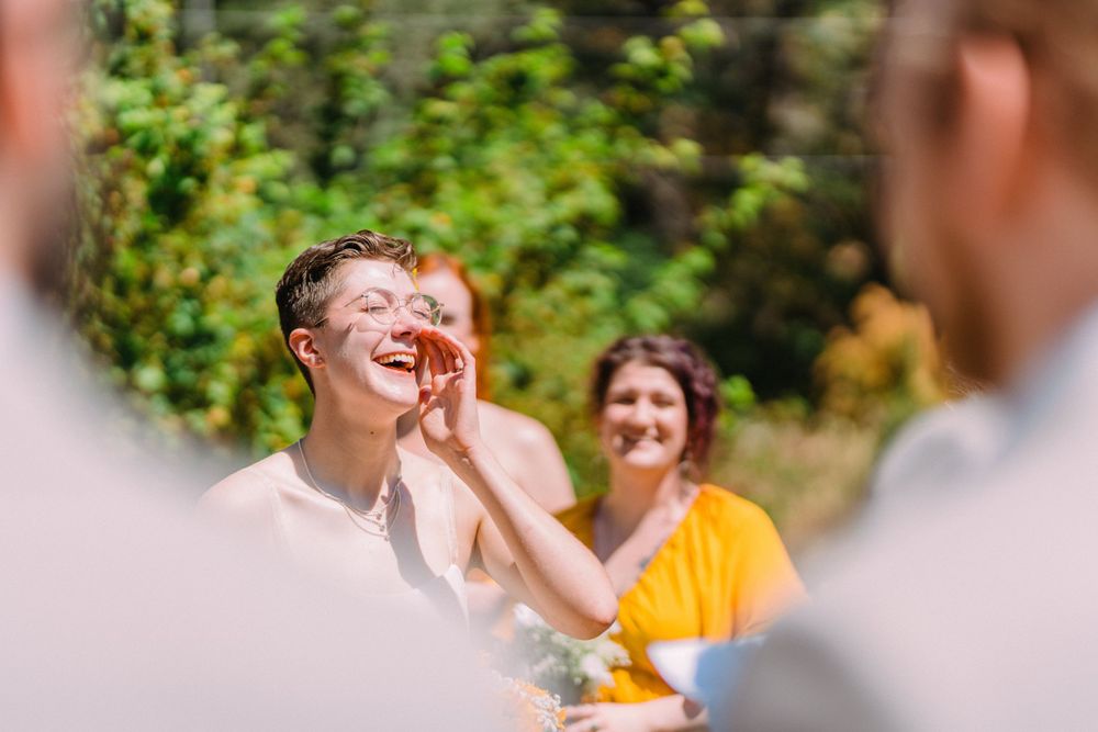 An emotional reaction is captured during a sunny outdoor wedding ceremony.