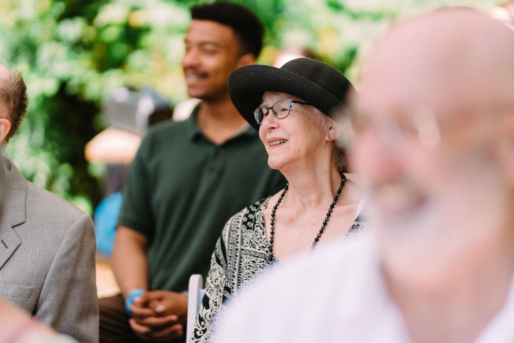 Wedding guests share joyful moments during an outdoor celebration surrounded by greenery.