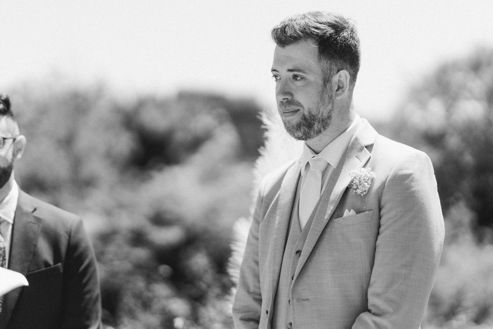 Black and white portrait of groom during outdoor wedding ceremony.