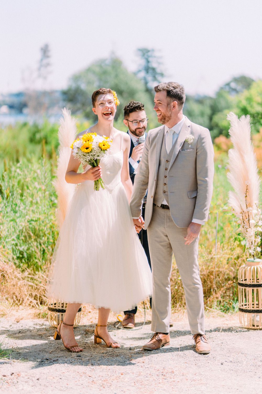 An outdoor wedding ceremony with laughter and joy featuring yellow sunflowers and natural scenery.