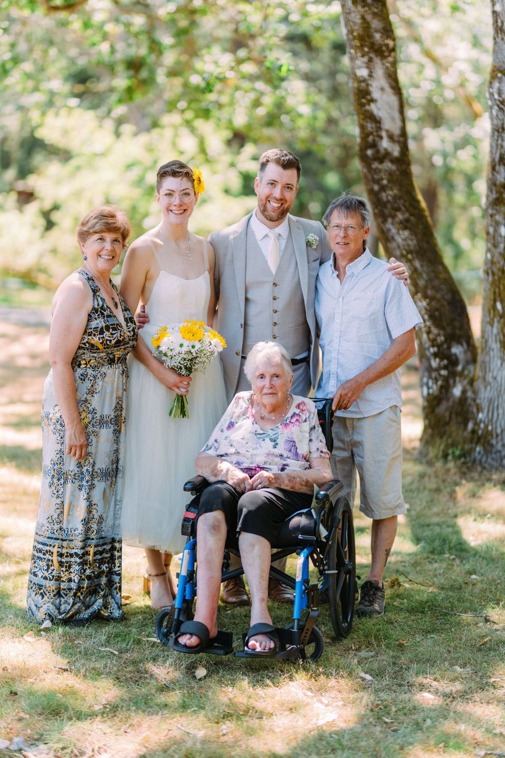 Family wedding photo outdoors with guests in summer attire.